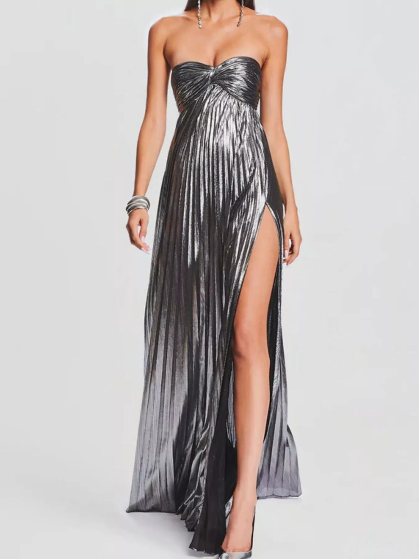 Woman wearing a strapless, gray gown with a slit on a white background