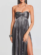 Woman wearing a strapless gray gown with a high slit on a plain background