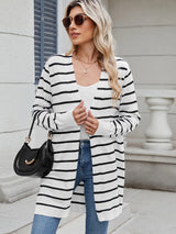 Woman wearing a black and white striped open front cardigan with blue jeans, layered over a white tank top for a casual everyday outfit.