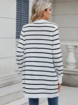 Woman wearing a black and white striped open front cardigan with blue jeans, layered over a white tank top for a casual everyday outfit.
