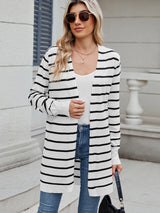 Woman wearing a black and white striped open front cardigan with blue jeans, layered over a white tank top for a casual everyday outfit.