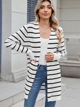 Woman wearing a black and white striped open front cardigan with blue jeans, layered over a white tank top for a casual everyday outfit.