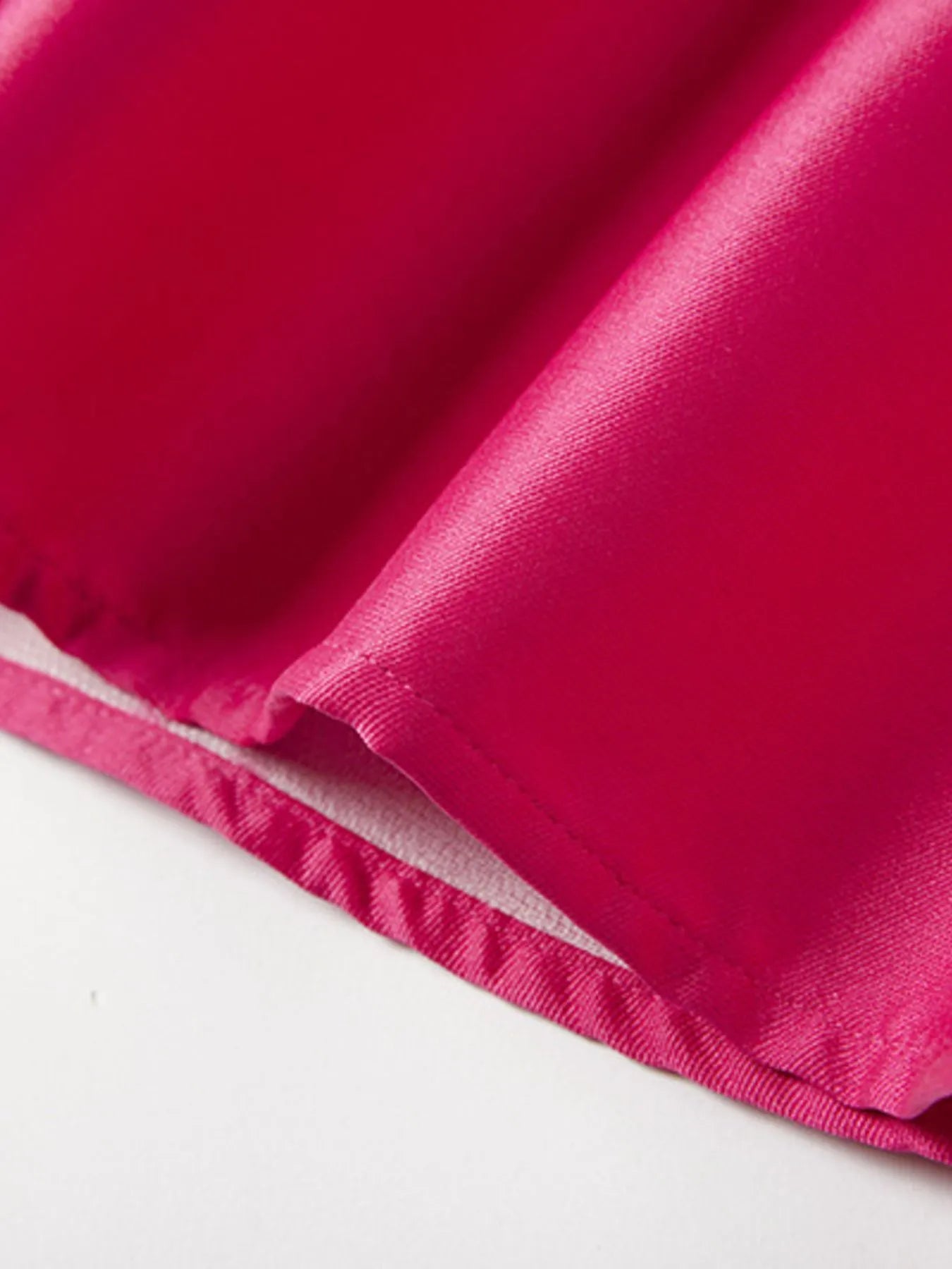 Close-up of a rose red satin fabric with a white background