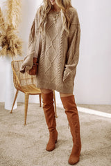 Woman wearing a tan cable knit long sleeve sweater dress styled with knee-high brown boots and layered gold necklaces.