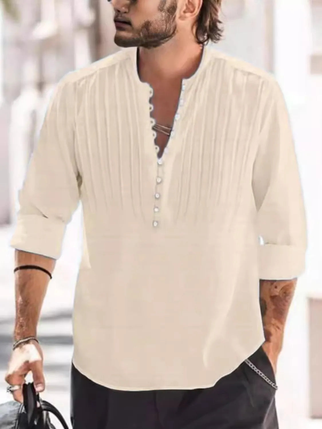 Man wearing a tan button-detail long sleeve cotton polo with rolled sleeves and black pants.