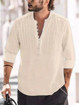 Man wearing a tan button-detail long sleeve cotton polo with rolled sleeves and black pants.