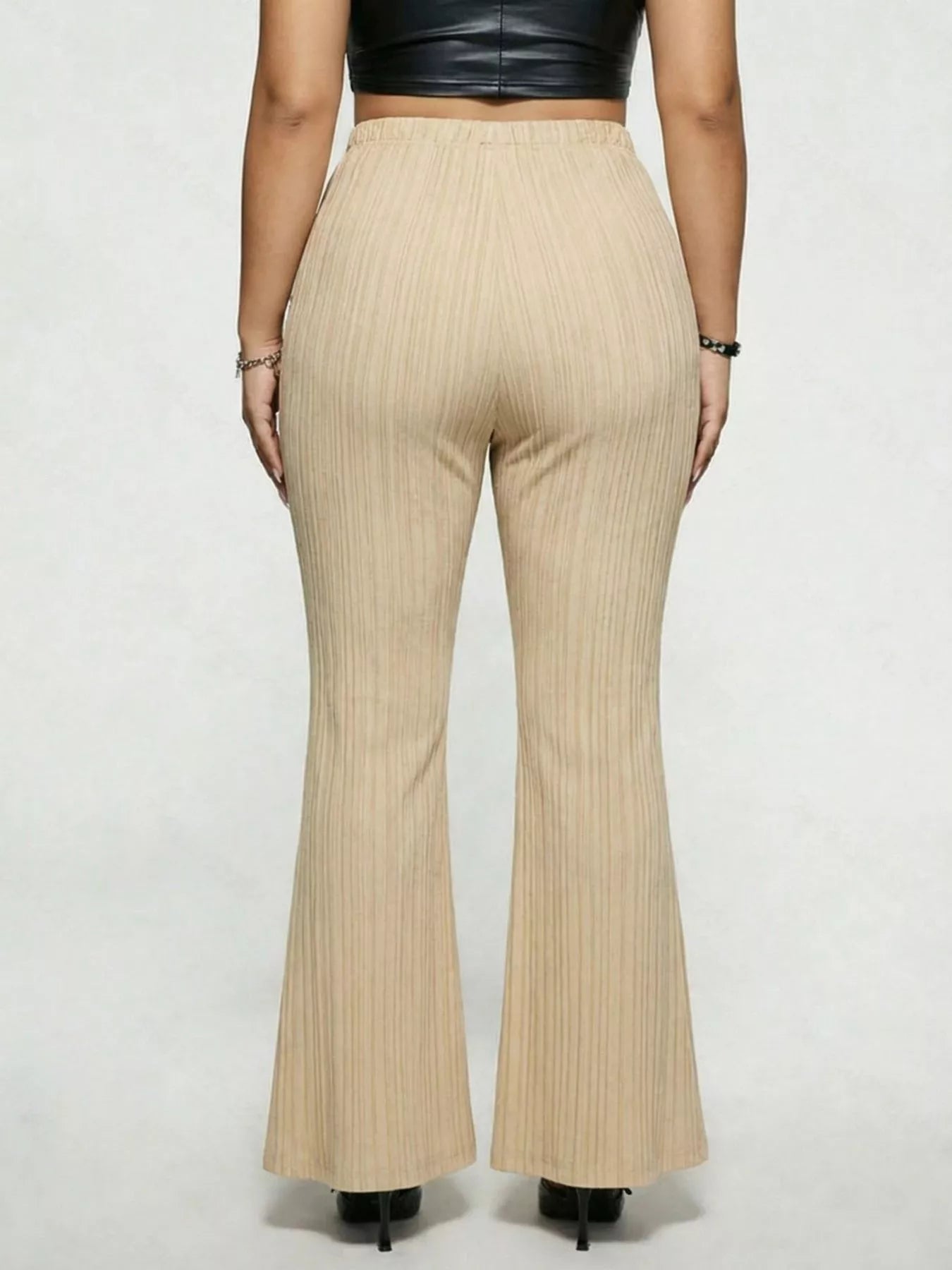 Model wearing tan plus-size high-waisted flare pants styled with pointed-toe heels for an elegant and sophisticated look.