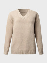 Woman wearing a tan V-neck long sleeve knit top with ribbed neckline and cuffs, styled with black denim shorts.