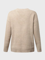 Woman wearing a tan V-neck long sleeve knit top with ribbed neckline and cuffs, styled with black denim shorts.
