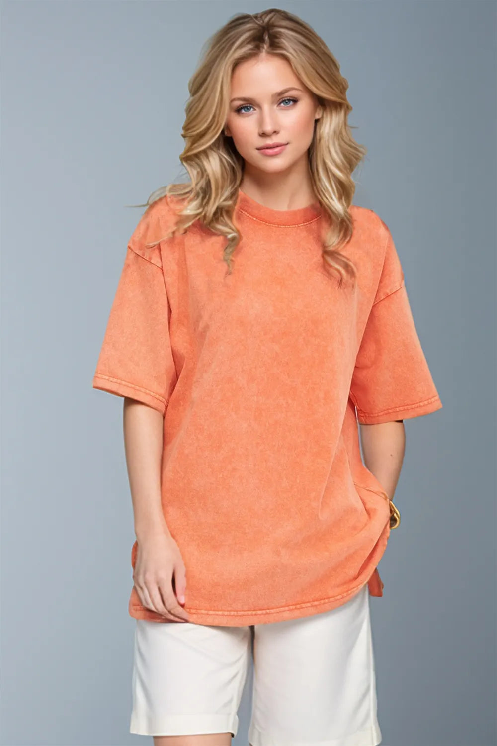 Woman wearing an oversized tangerine Basic Bae round-neck half-sleeve T-shirt styled with dark denim jeans and a long pendant necklace for a relaxed, casual look.