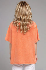 Woman wearing an oversized tangerine Basic Bae round-neck half-sleeve T-shirt styled with dark denim jeans and a long pendant necklace for a relaxed, casual look.