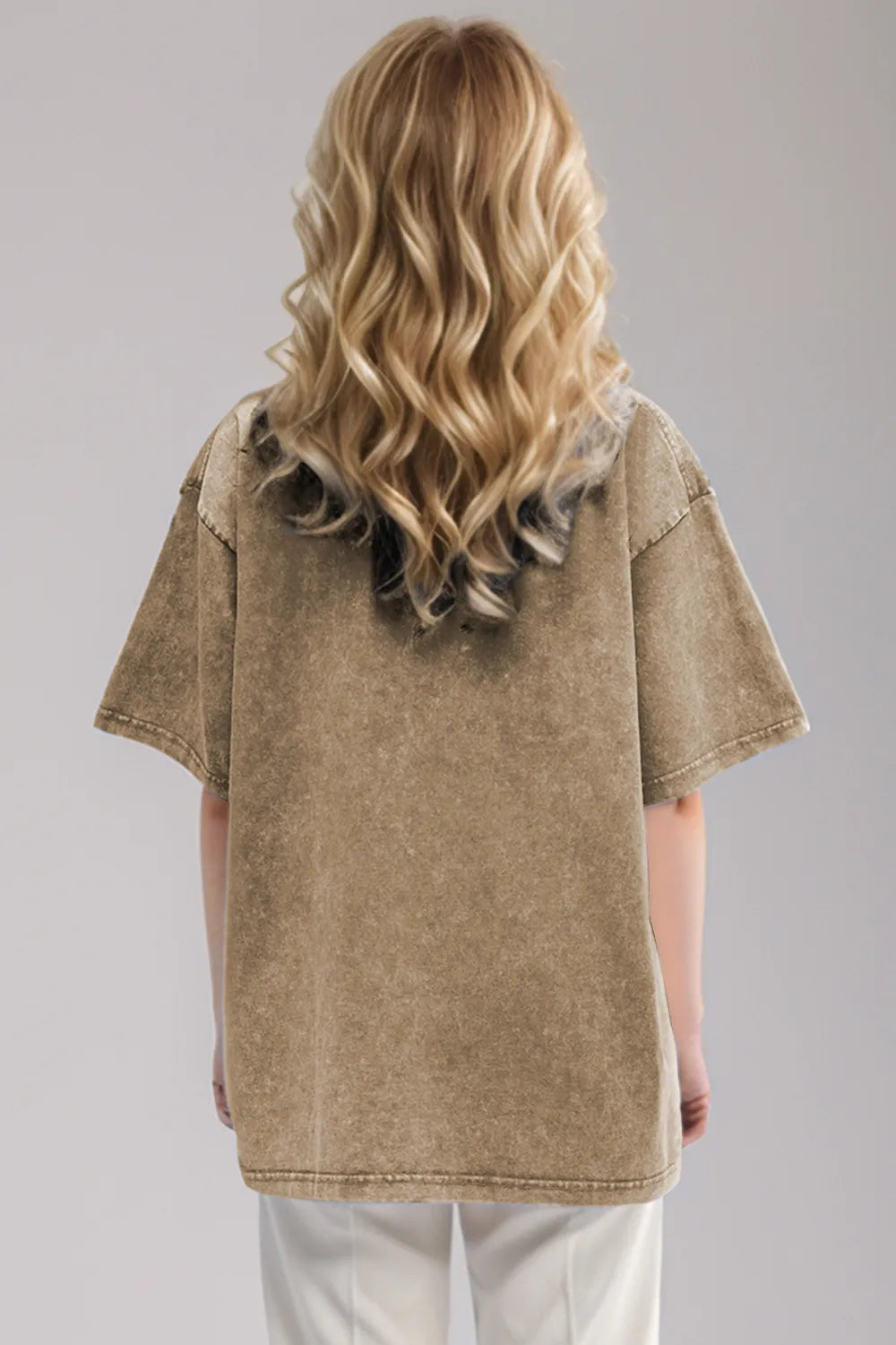 Woman wearing an oversized taupe Basic Bae round-neck half-sleeve T-shirt styled with dark denim jeans and a long pendant necklace for a relaxed, casual look.