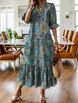 Woman wearing a teal bohemian paisley print midi dress with three-quarter sleeves and ruffled hem.
