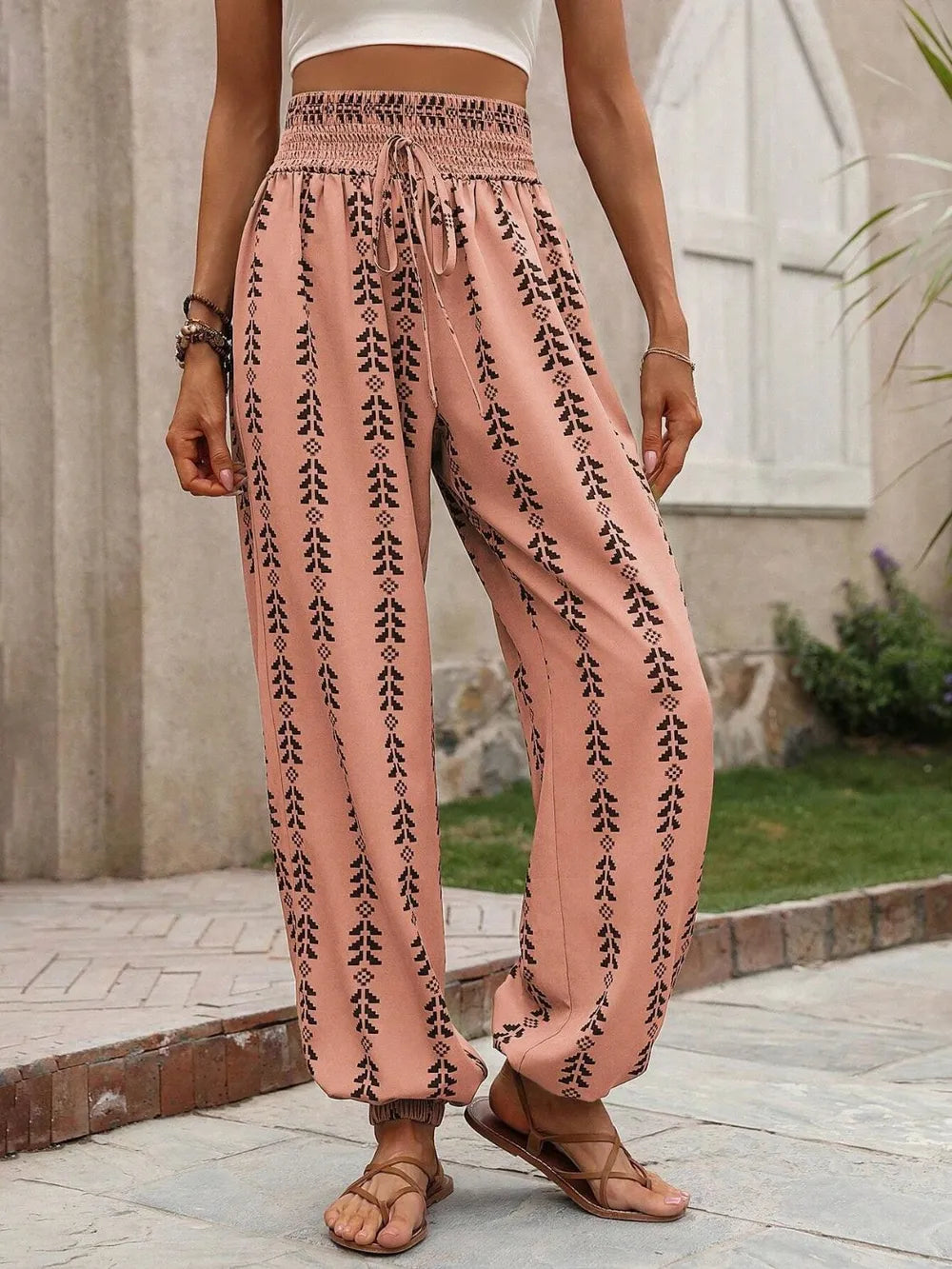 Vacation Ready. Person wearing burnt coral patterned pants outdoors on a stone path. Burnt coral front view