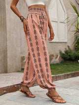 Person wearing burnt coral pants with black patterns and sandals, standing outdoors. side view
