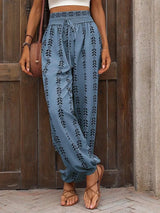 Person wearing cerulean embroidered pants standing against a wooden wall.