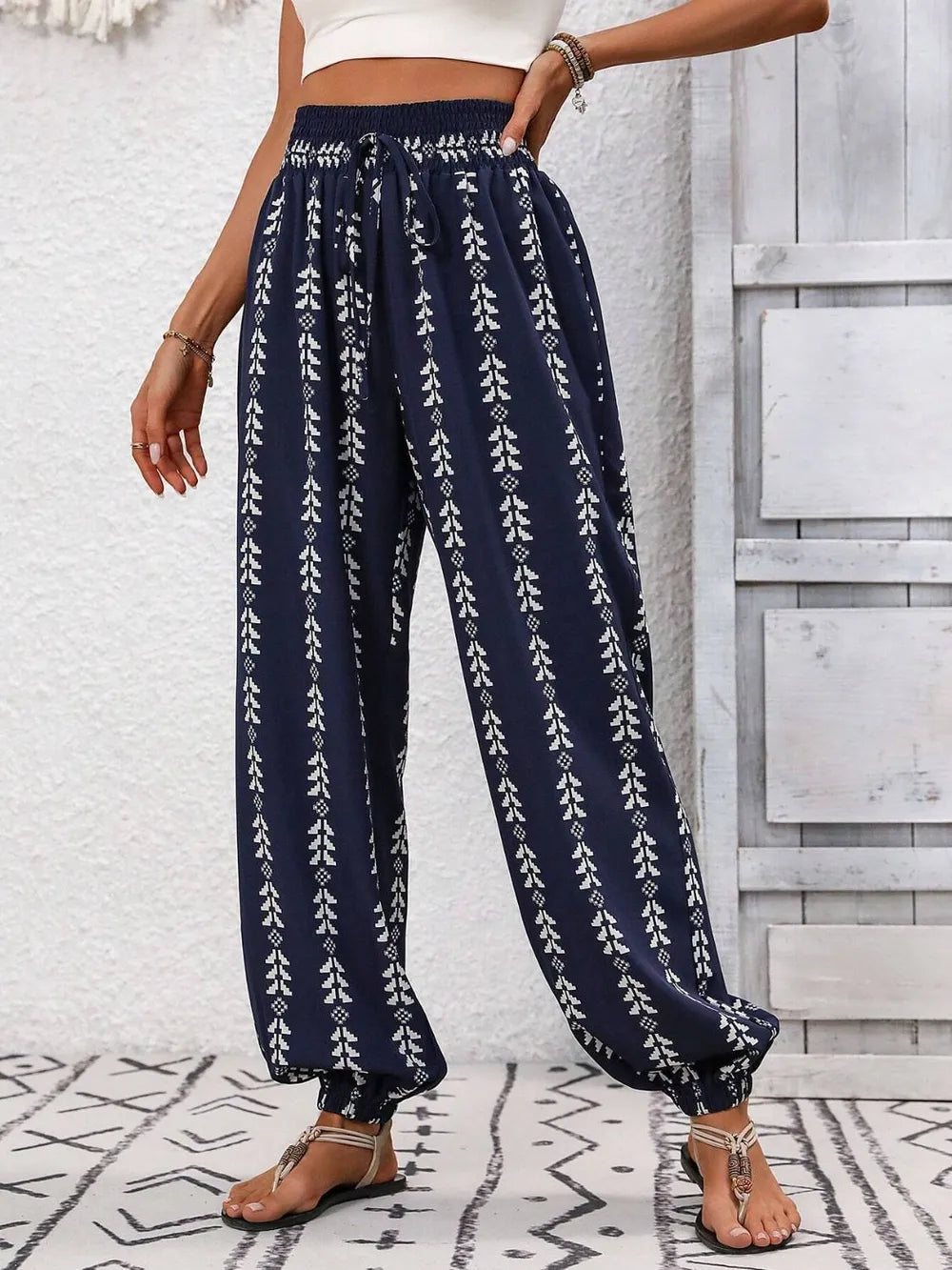 Navy blue pants with white floral pattern worn by a person against a light gray wall.