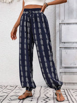 Navy blue pants with white floral pattern worn by a person against a light gray wall.