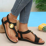Black sandals with gold accents worn by a person, with a blue background and pineapple decor.
