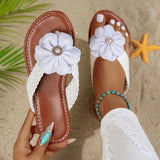 Brown sandals with white flower decorations on a sandy background