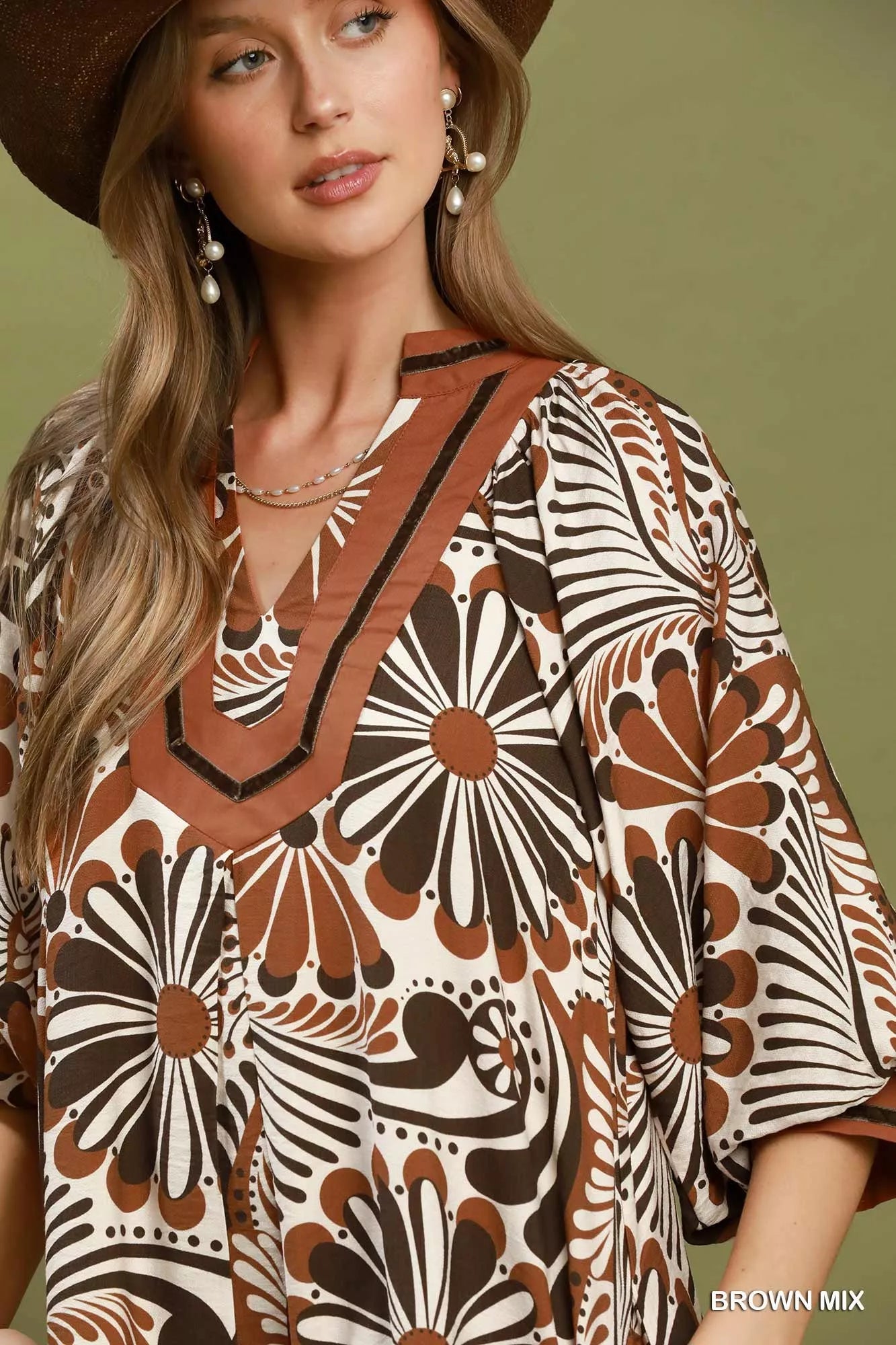 Woman wearing a patterned dress with a brown and beige design against a green background