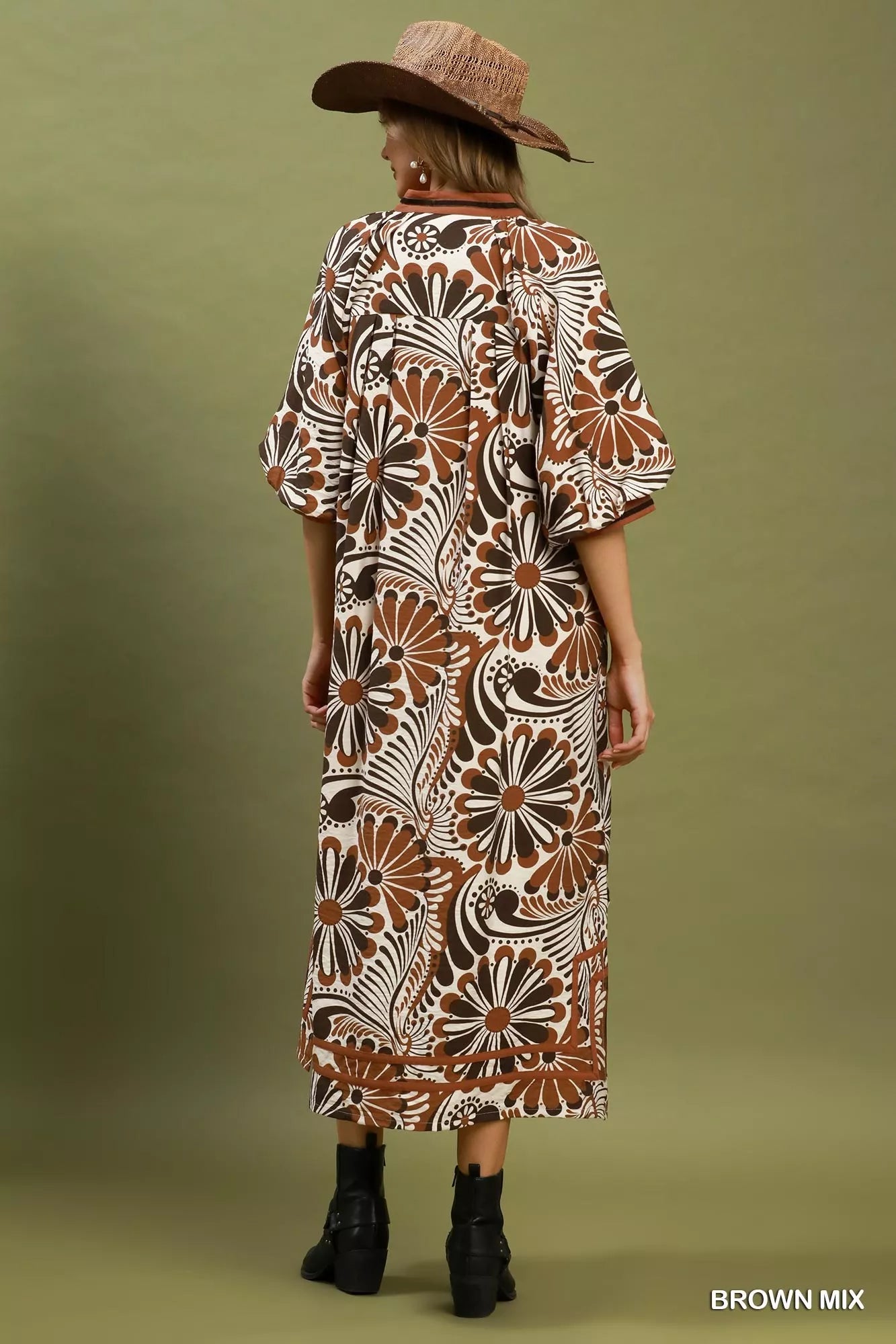 Woman wearing a patterned dress and hat on a green background