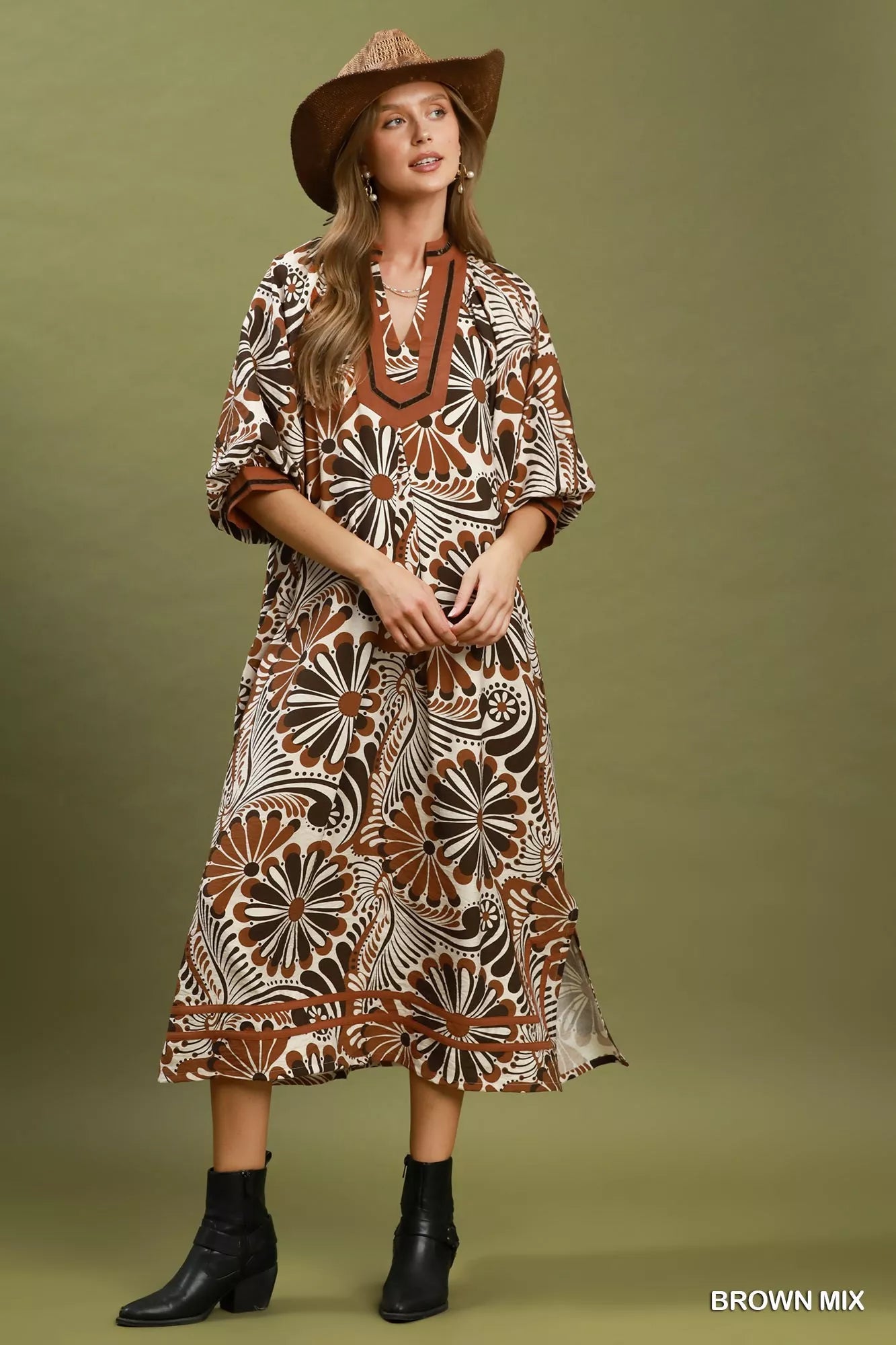 Woman wearing a patterned dress and hat on a green background