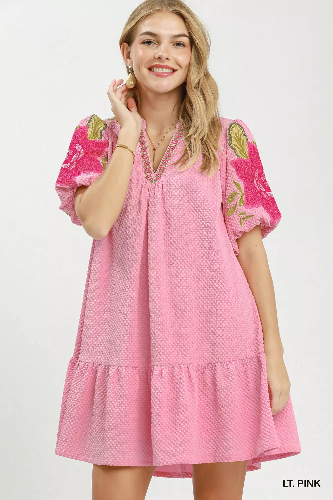 Woman wearing a pink dress with floral patterns on a white background