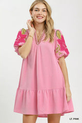 Woman wearing a pink dress with floral patterns on a white background
