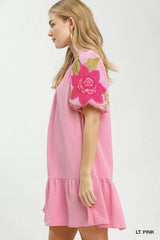 Woman wearing a light pink dress with floral design on a white background