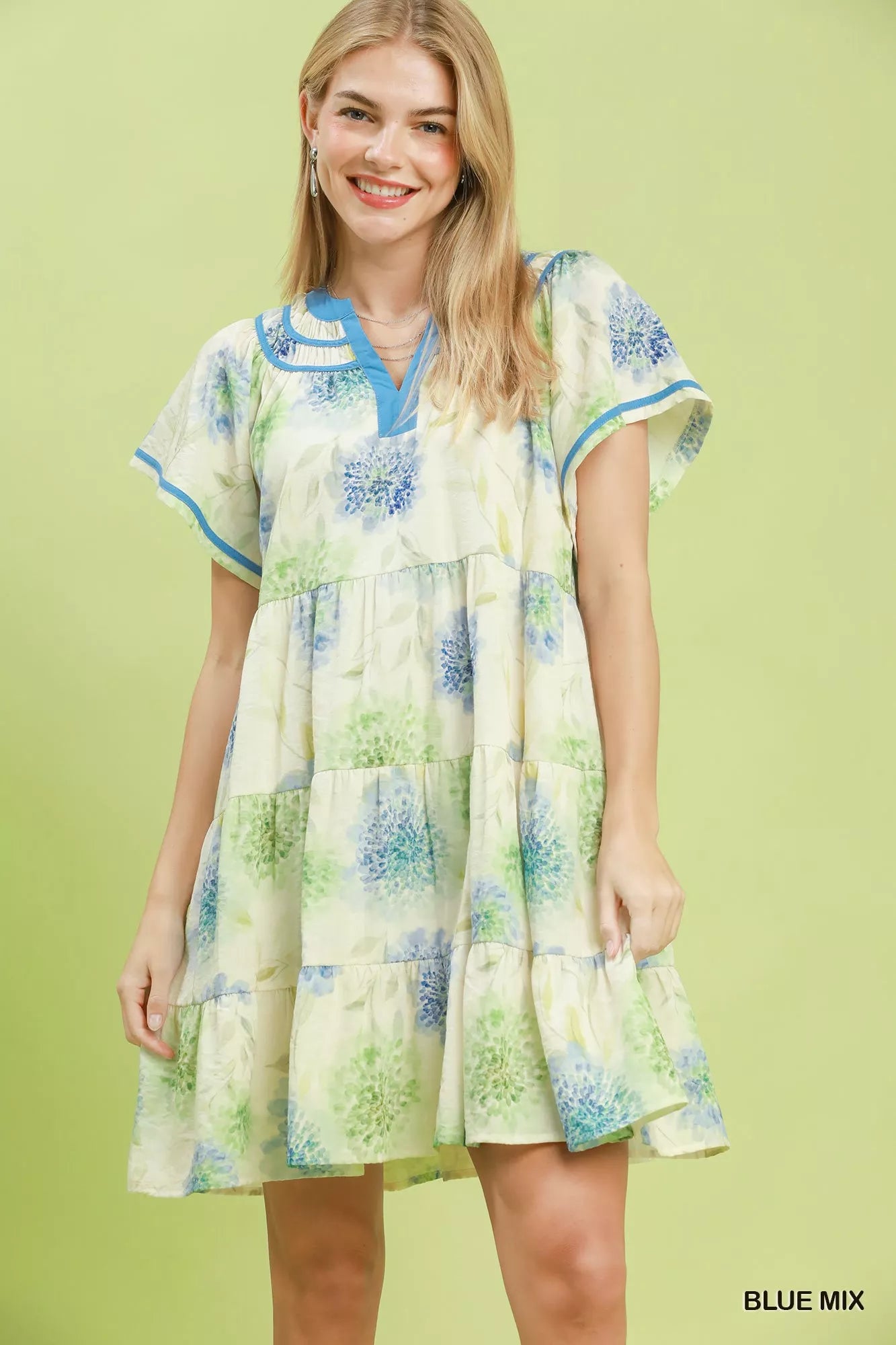 Woman wearing a floral dress with a blue mix pattern on a green background