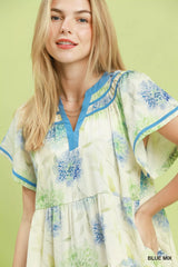 Woman wearing a floral dress with blue and green accents on a light green background