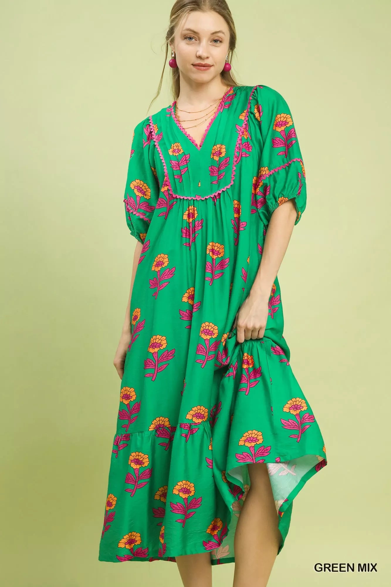Woman wearing a green dress with floral patterns on a light green background