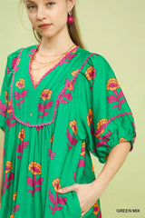 Green dress with floral embroidery on a model against a light green background