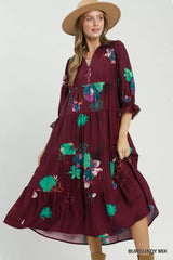 Woman wearing a burgundy dress with floral embroidery on a white background