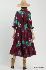 Woman wearing a burgundy floral dress with a beige hat and boots on a white background