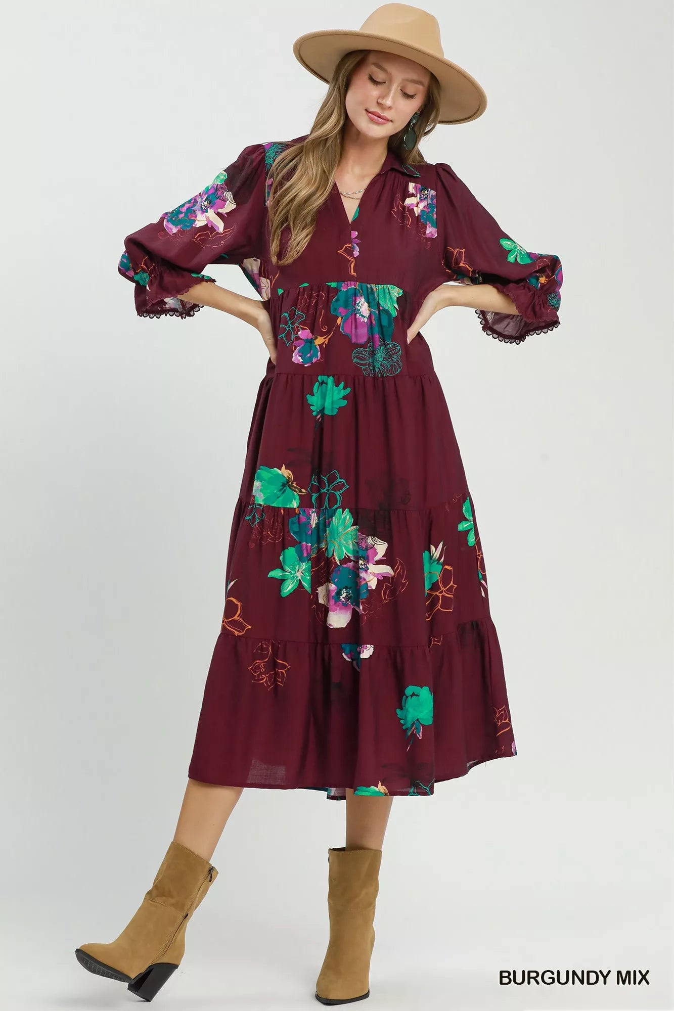 Woman wearing a burgundy dress with floral embroidery and tan boots on a white background