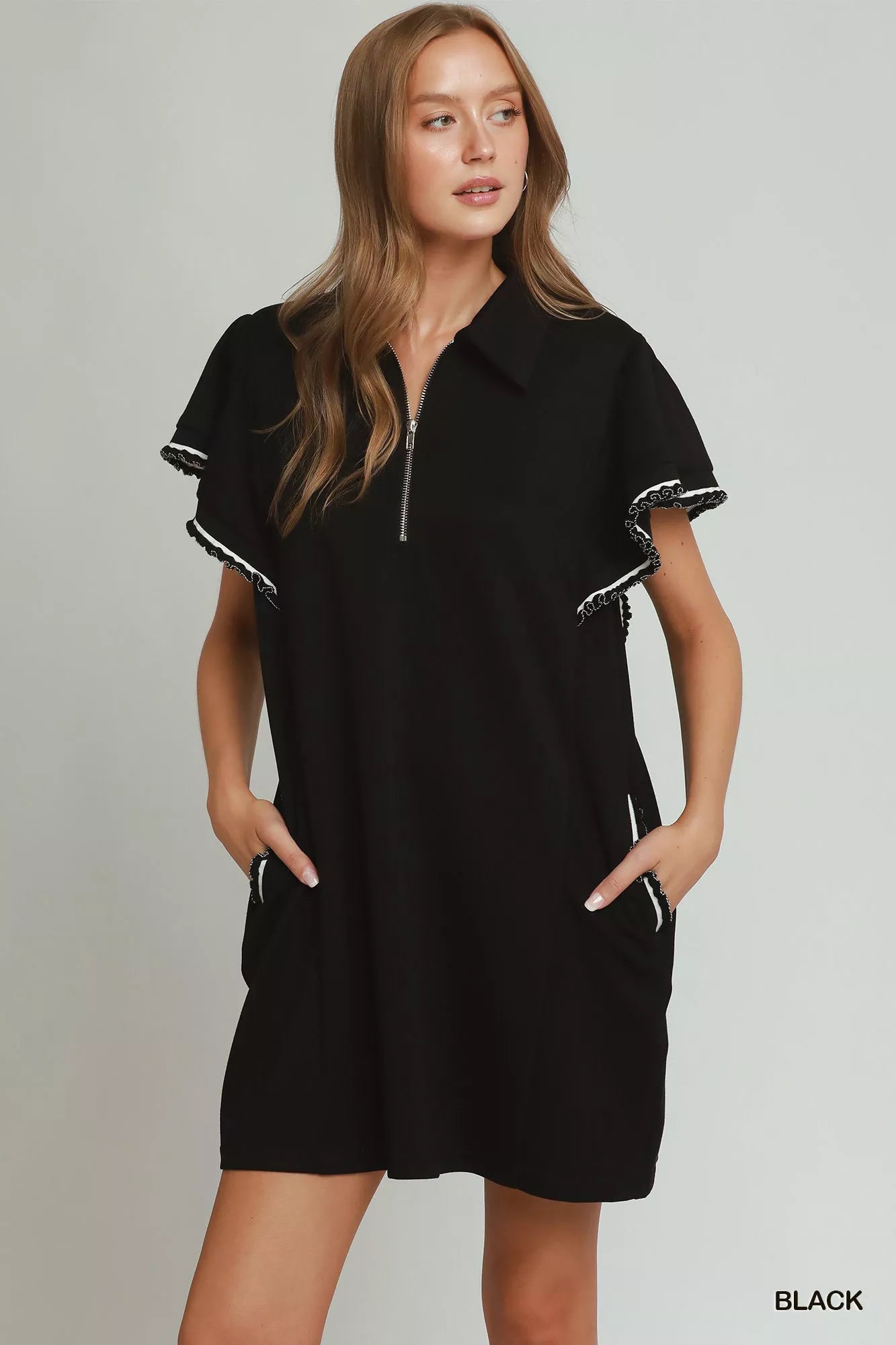Woman wearing a black dress with white trim on a gray background