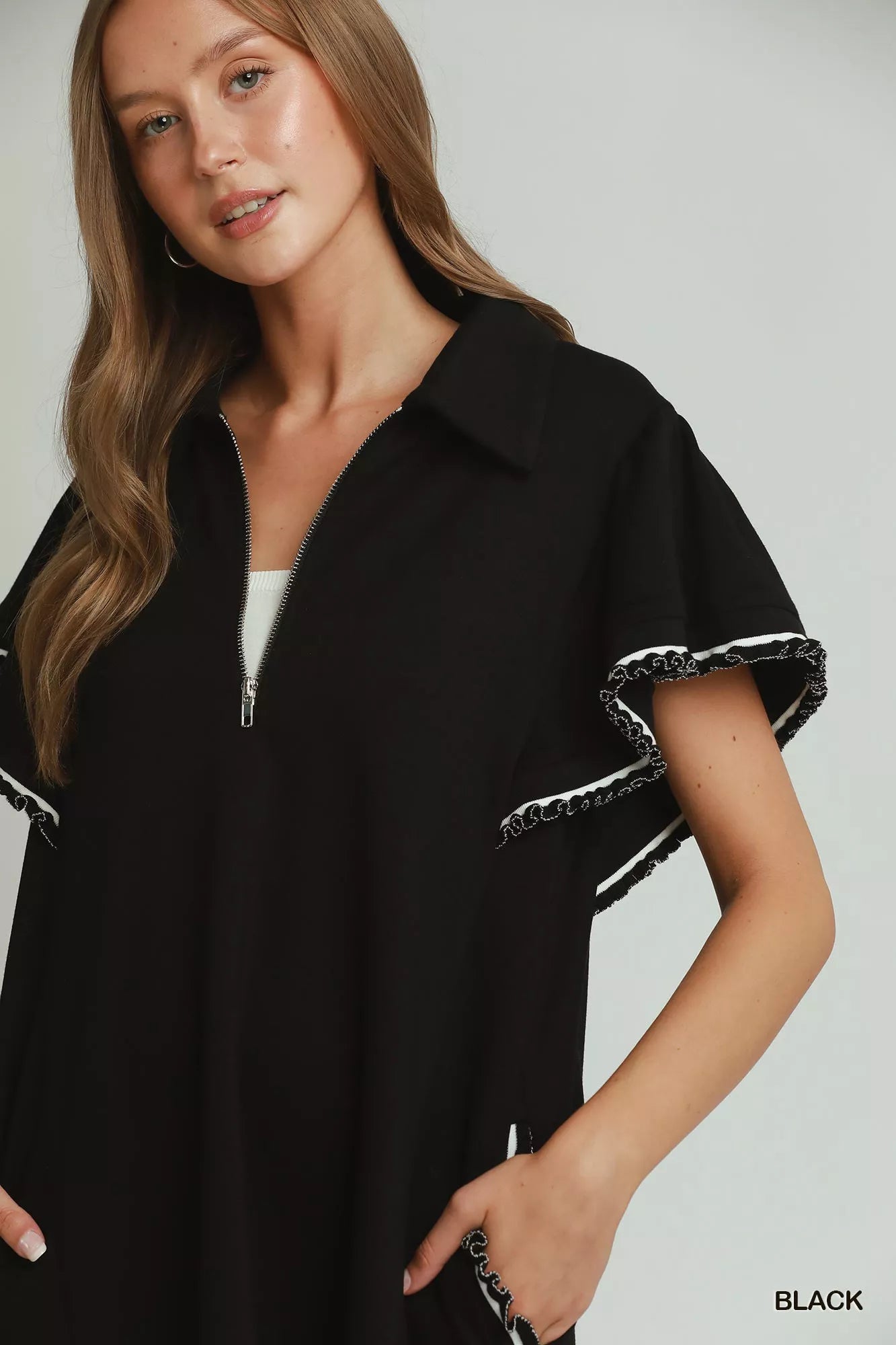 Woman wearing a black dress with white trim on a plain background