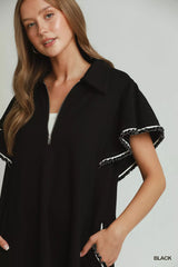 Woman wearing a black dress with white trim on a plain background