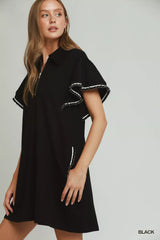 Woman wearing a black dress with ruffled sleeves on a gray background