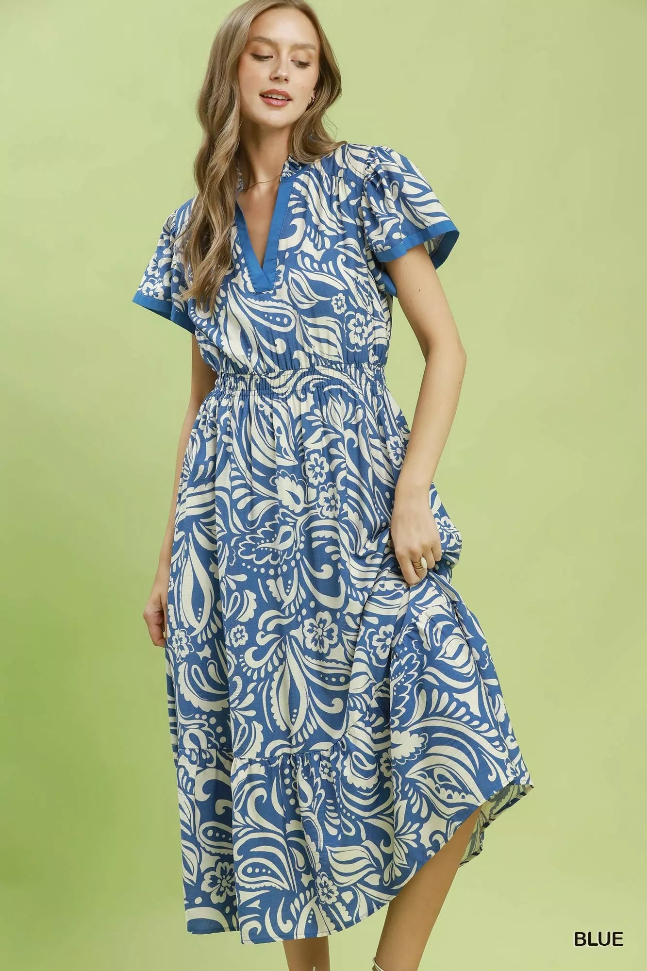 Woman wearing a blue and white patterned dress on a green background