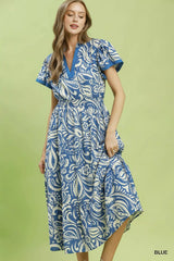 Woman wearing a blue and white patterned dress on a green background