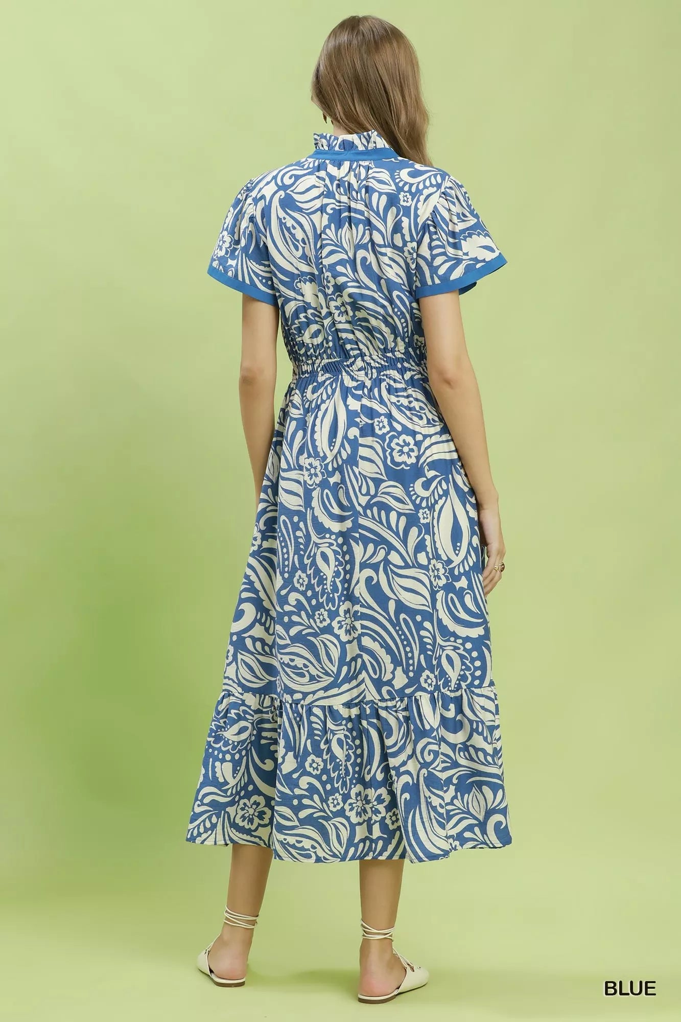 Woman wearing a blue and white patterned dress on a green background