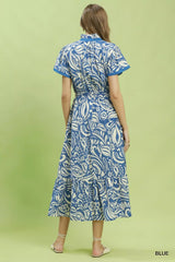 Woman wearing a blue and white patterned dress on a green background