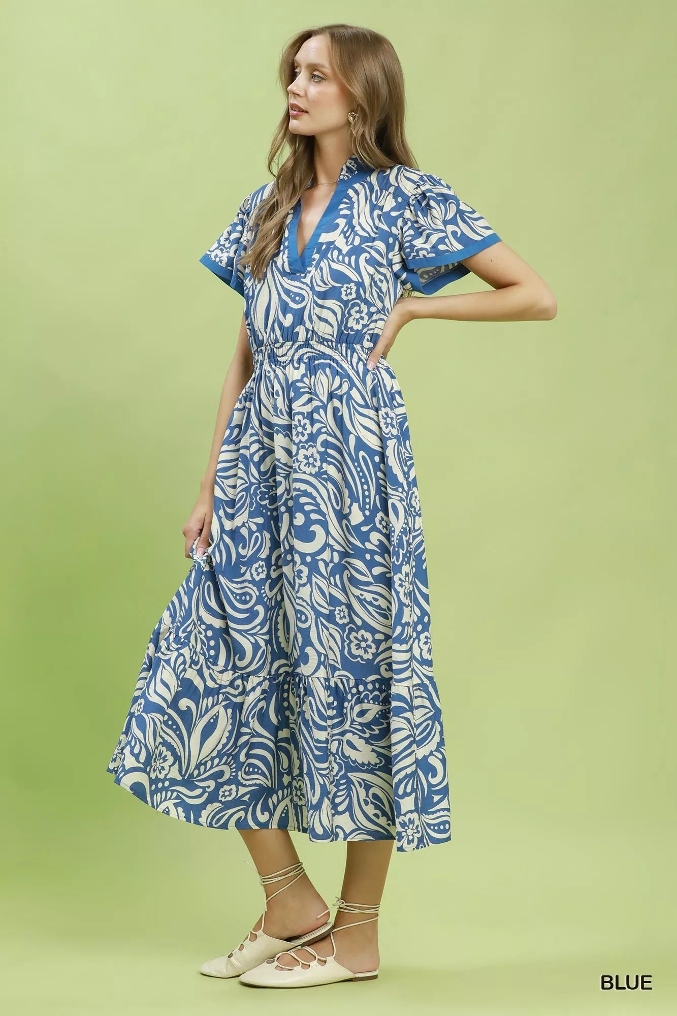 Woman wearing a blue and white patterned dress on a green background