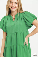 Woman wearing a green dress with puff sleeves on a white background