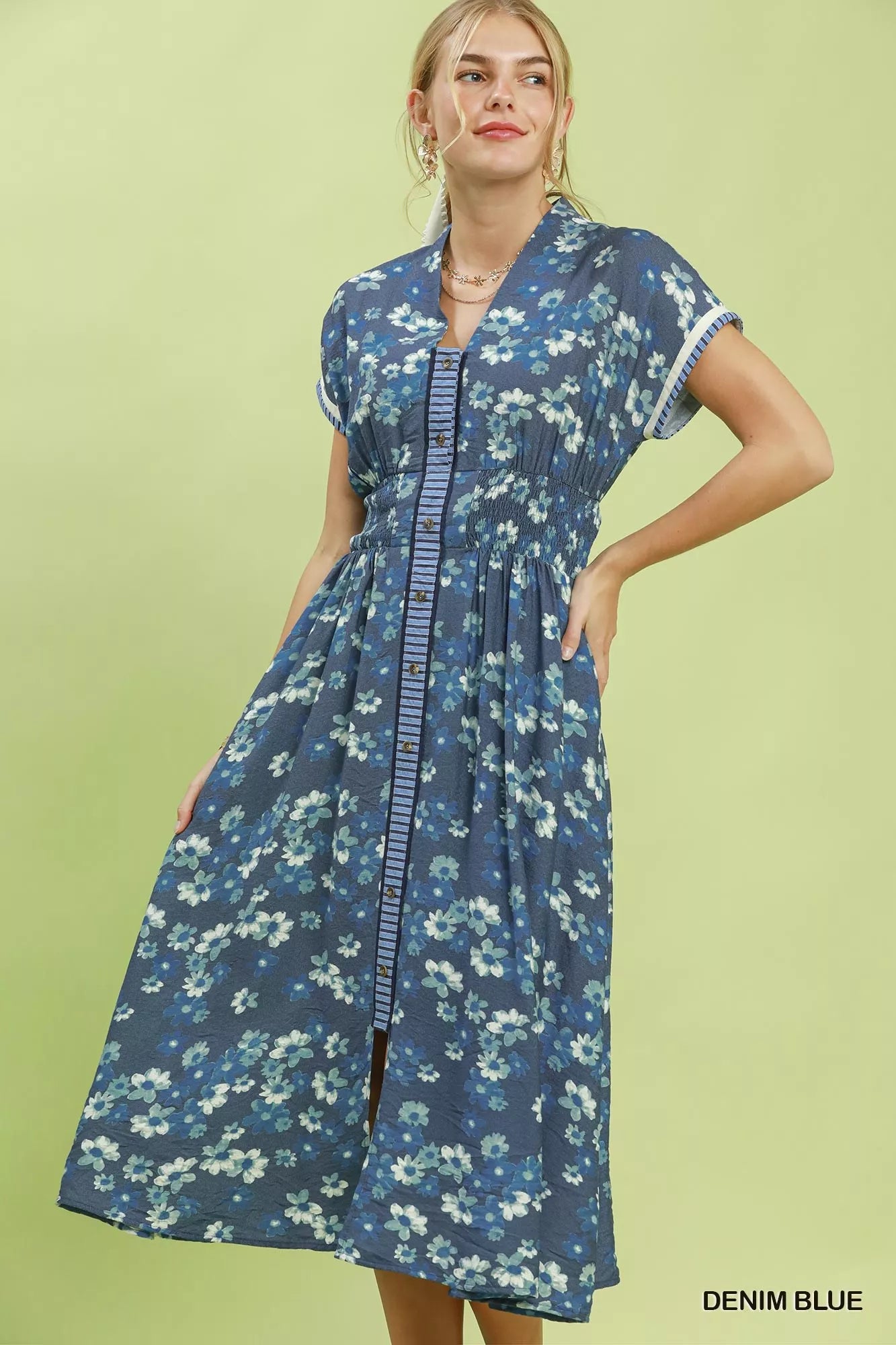 Woman wearing a denim blue floral dress on a green background