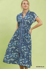 Woman wearing a denim blue floral dress on a green background