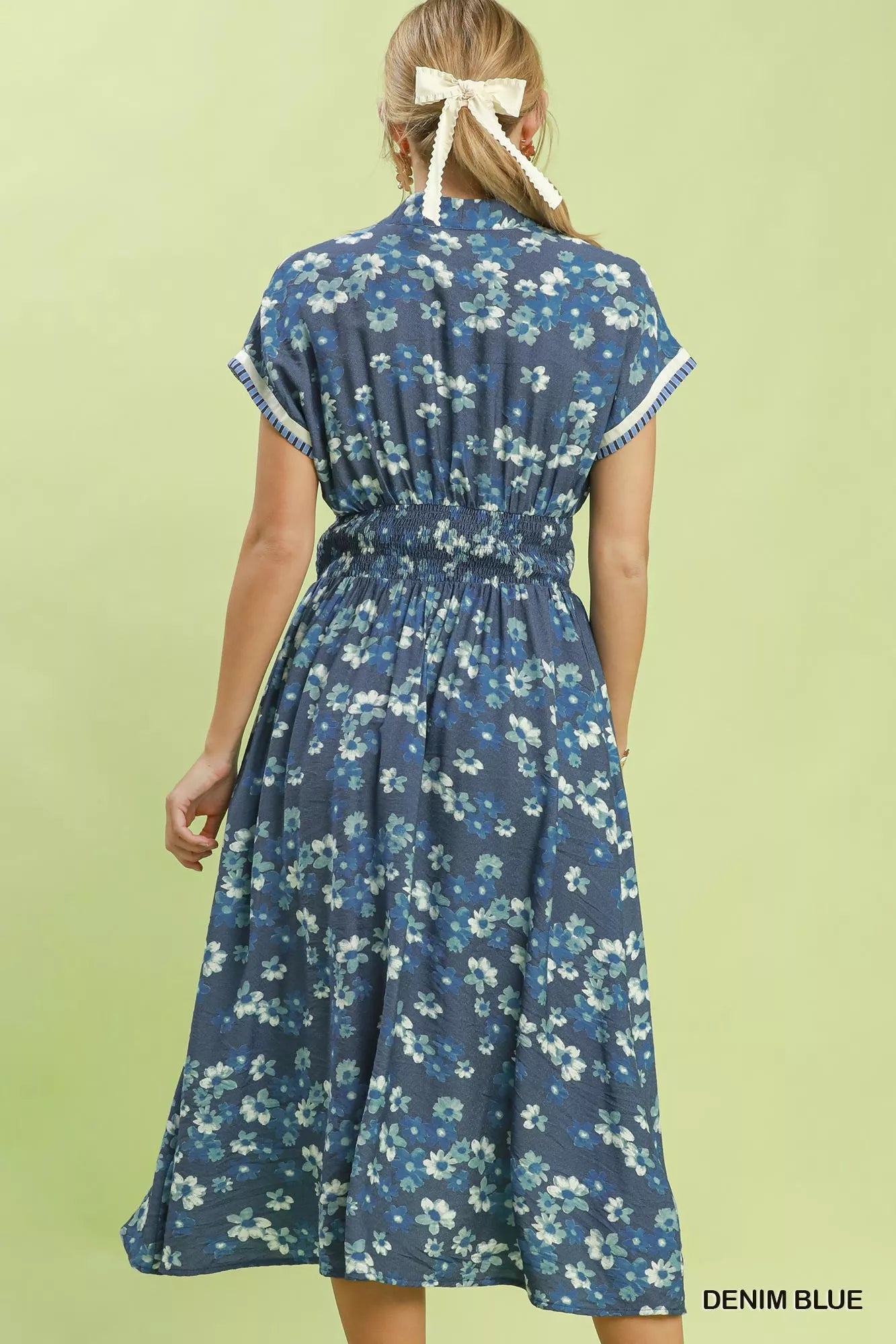 Woman wearing a denim blue floral dress on a light green background